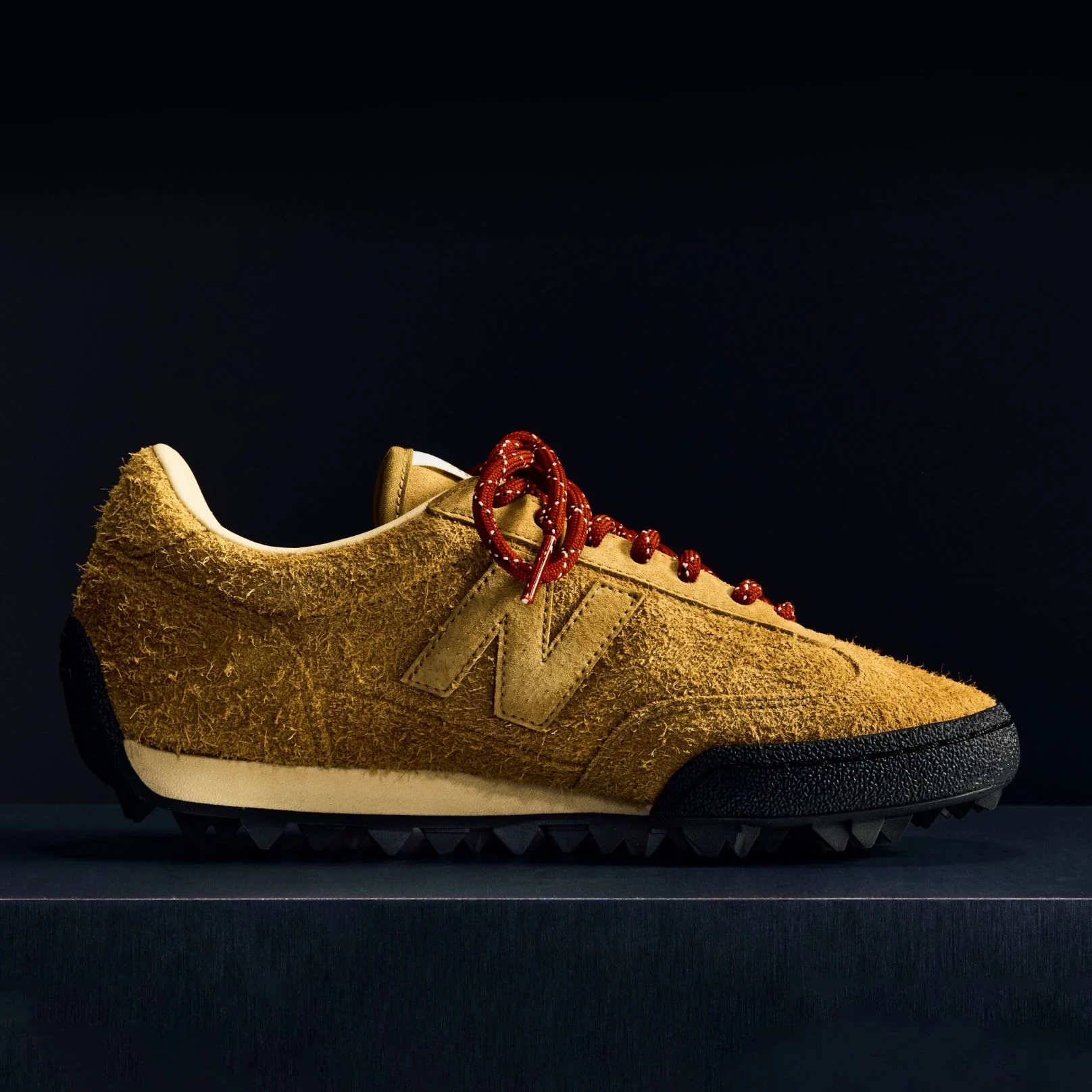 A brown suede Gator Run shoe on a black background.