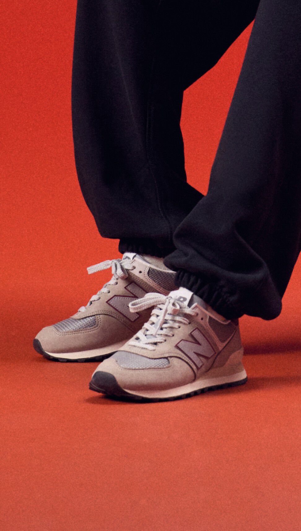 Young man standing on a red background wearing a black pants.
