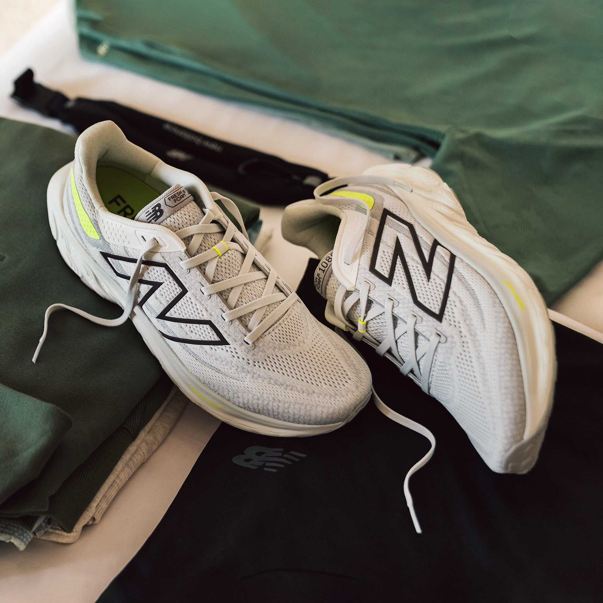 A pair of white, grey, and green 1080v13 shoes on a hardwood floor.