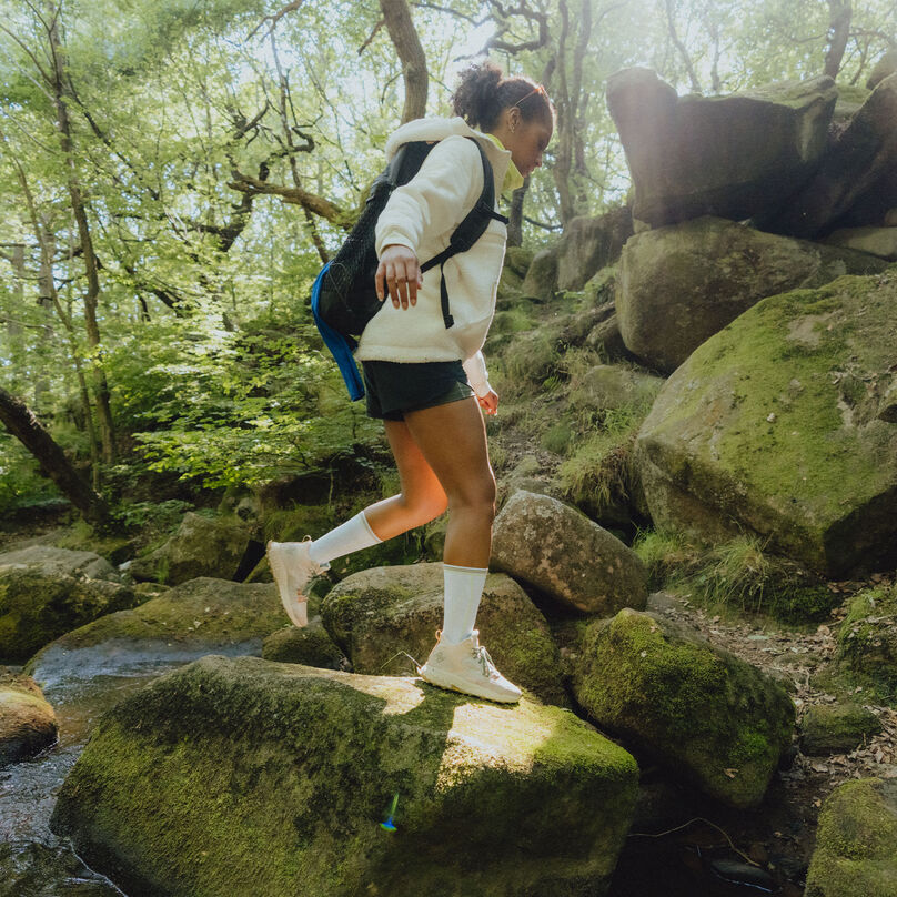 Woman hiking in the woods, wearing NB outdoor apparel and a pair of Fresh Foam X Hierro HT