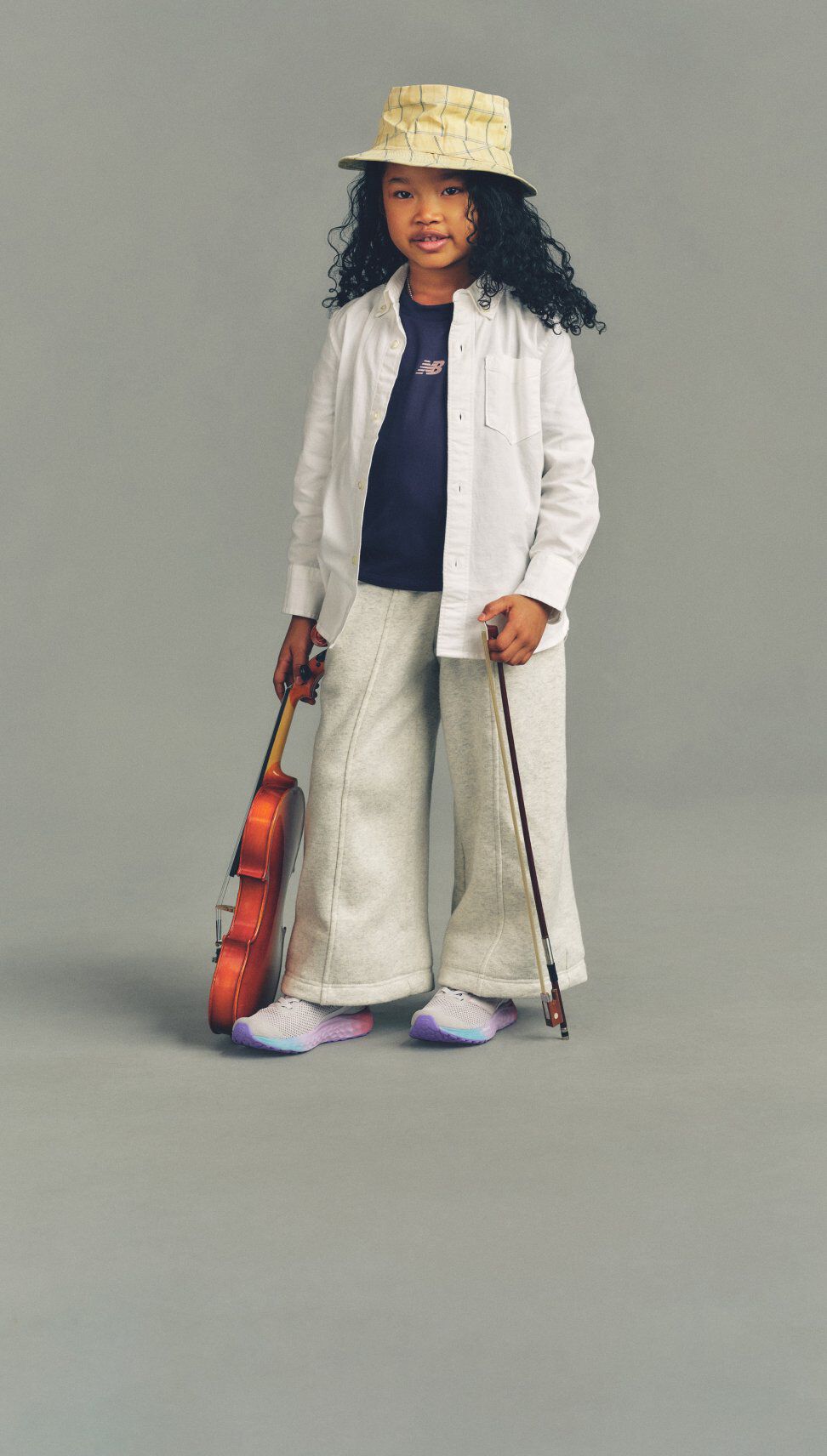 Girl wearing Fresh Foam Arishi shoes standing against a grey studio background.