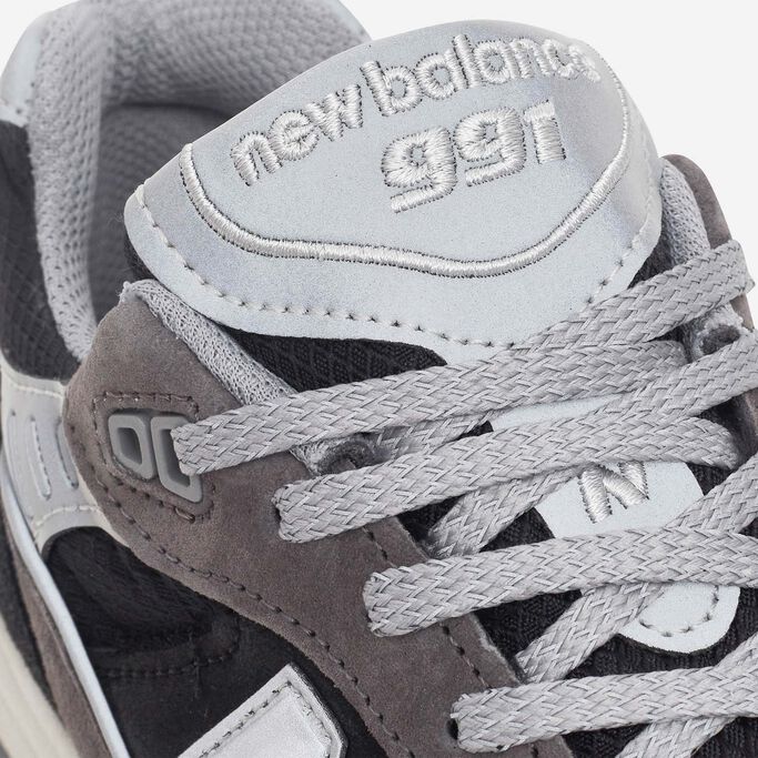Close-up view of the laces and tongue of a black and silver NB Made in UK 991 sneaker