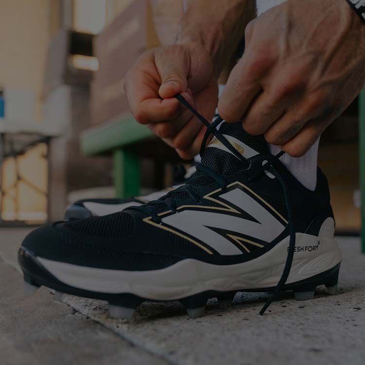 Baseball athlete tying his cleats in a dugout. 