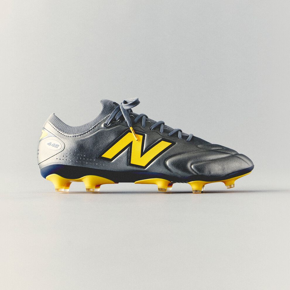 Gray and yellow New Balance soccer cleat with a streamlined synthetic upper and molded studs displayed against a clean white background.
