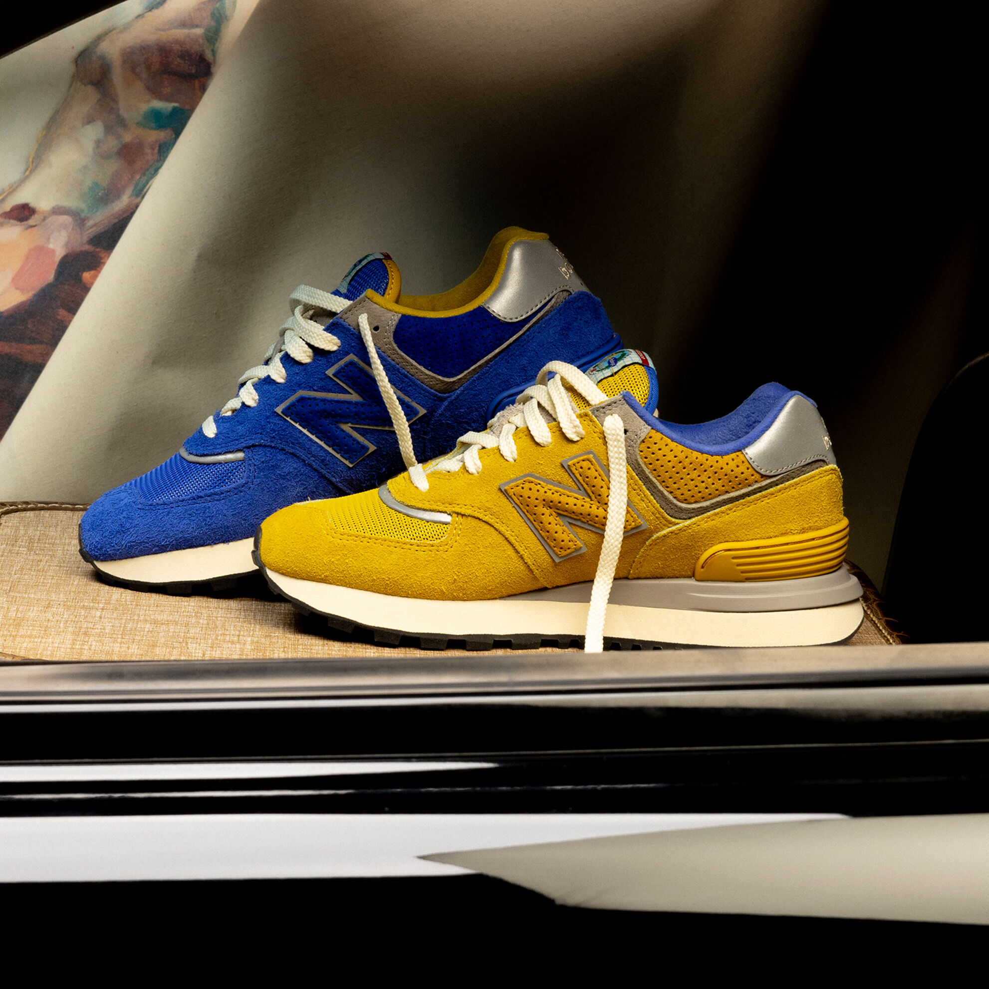 Yellow and Blue 574’s sitting inside a car on some luggage.