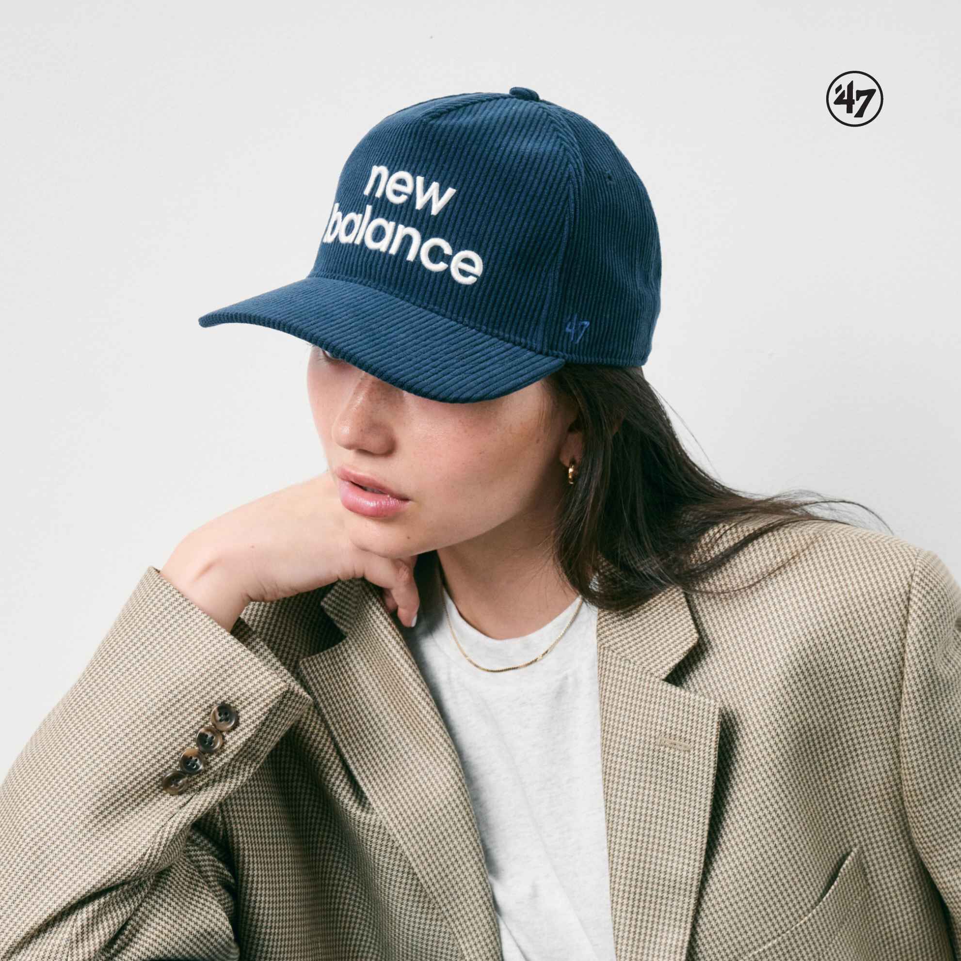 Mujer con gorra New Balance de pie frente a una pared blanca
