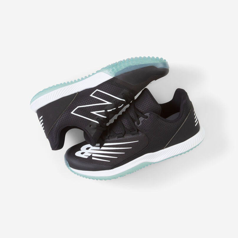 Pair of black turf shoes cradled together on a grey background.