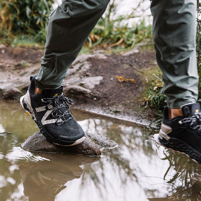 Person walking on rocks in stream wearing the New Balance Hierro v5 in black