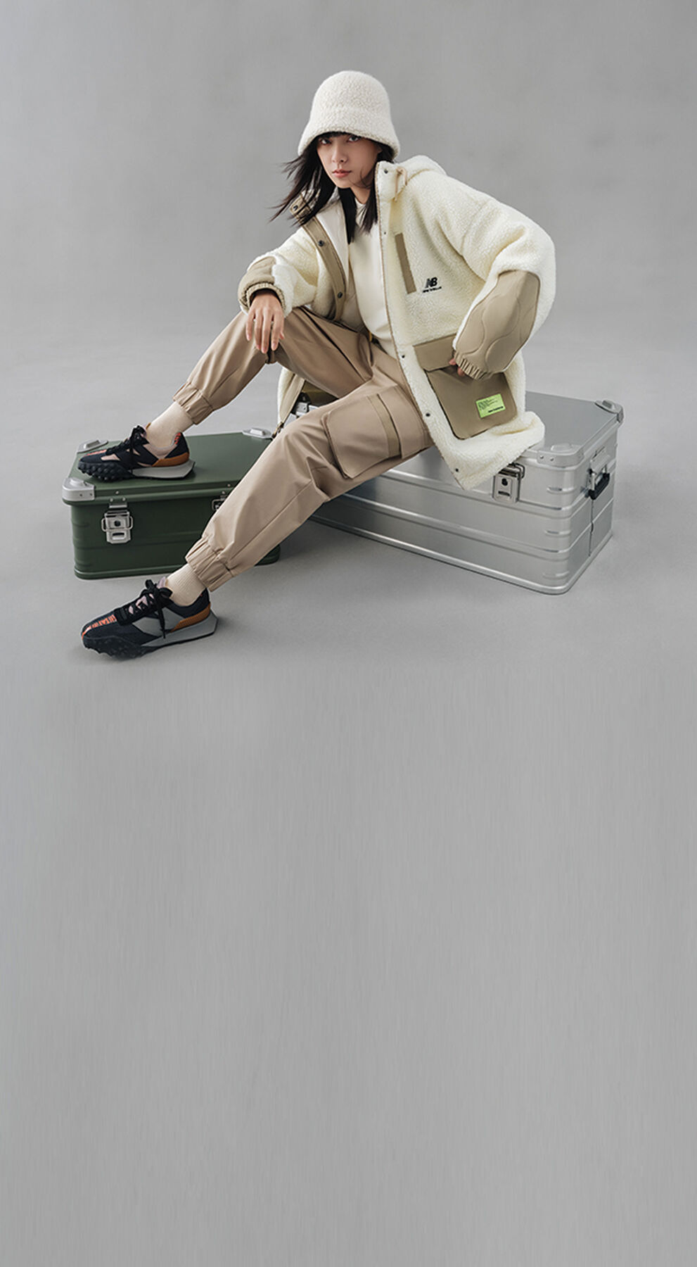Woman sitting on metal suitcases wearing Lunar New Year XC-72 and clothing collection.