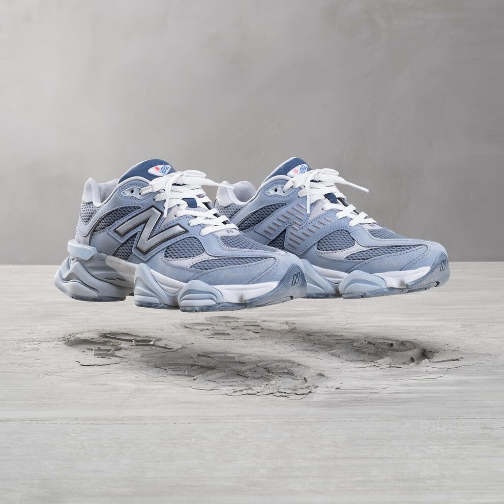 A pair of grey New Balance 9060 sneakers floating in the air above a lunar inspired background.