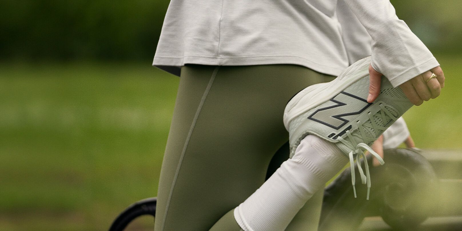 Woman pictured stretching outdoors in New Balance apparel and shoes, including the Fresh Foam X 860v14.