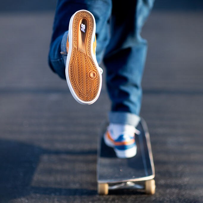 Waist-down view of a skateboarder wearing NB Numeric 272 skate shoes. The camera is focused on the vulcanized gum outsole.