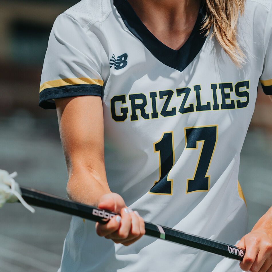 Crop of a female lacrosse player’s NB jersey as she moves down the field 