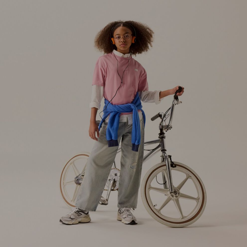 Joven con una camisa rosa al lado de una bicicleta.