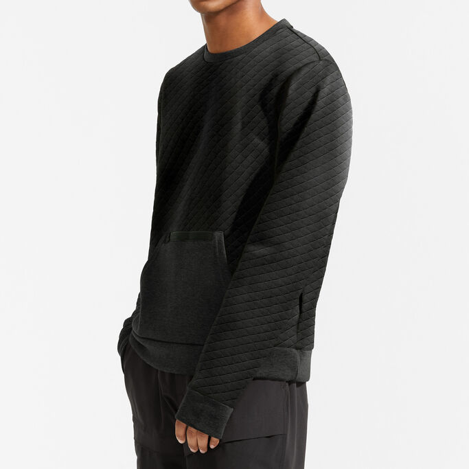 Young man standing to the side with his hand in his pockets showing sleeve of the pullover.