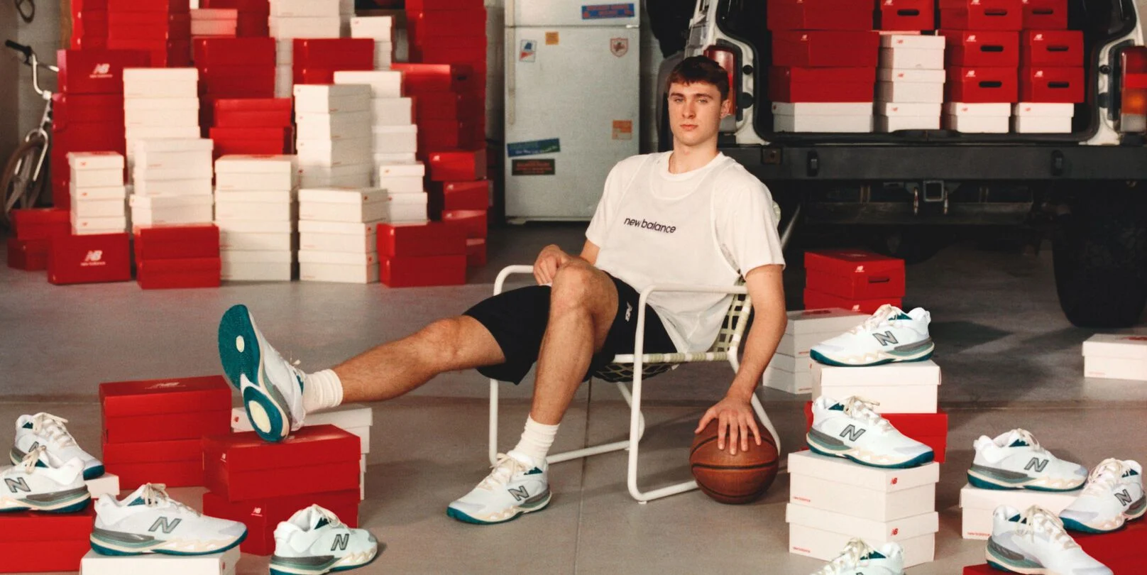 Young athlete sitting in a chair by his garage with shoes all around him.