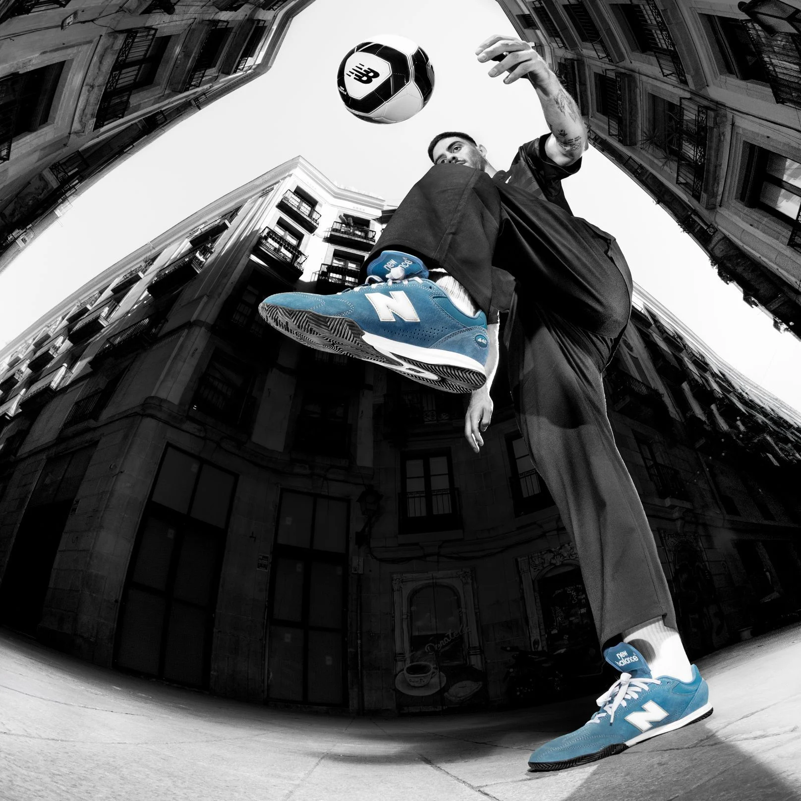 A person wearing Numeric 442 shoes, kicking a soccer ball.