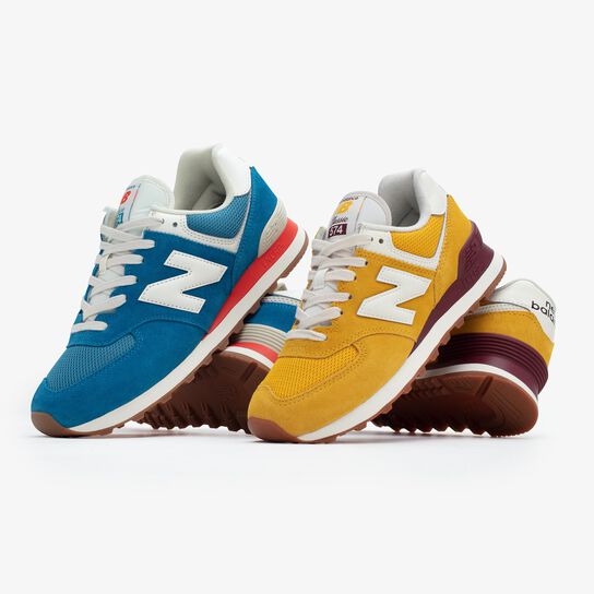 One blue and one yellow pair of NB 574 sneakers, each with gum soles, arranged in a group