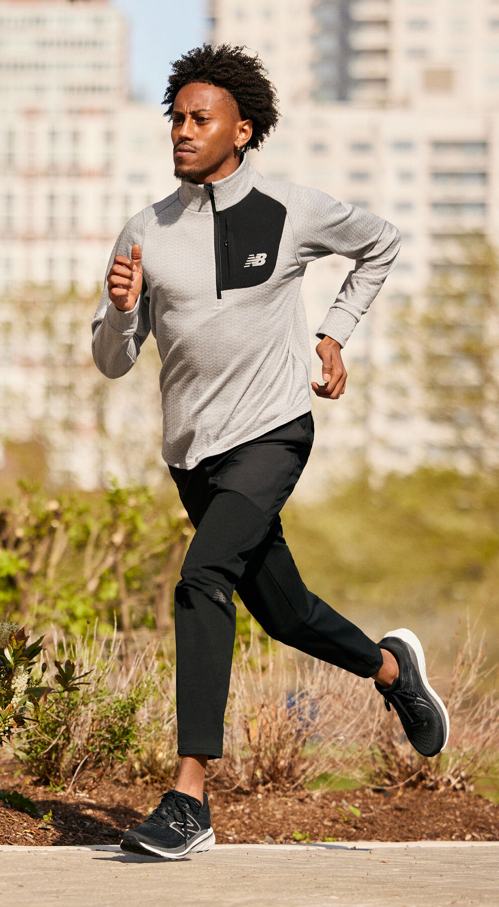 Young man in cream jacket and black tights running on a path.