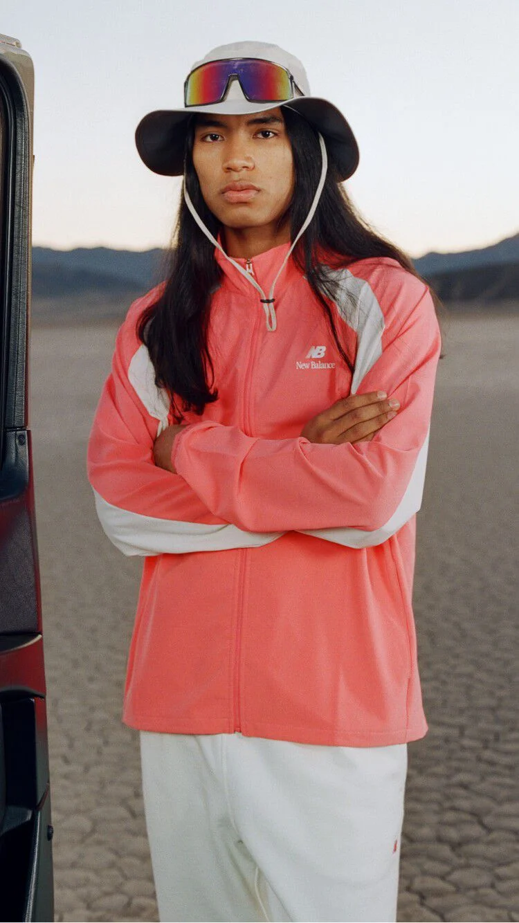 Man crossing his arms wearing a bucket hat with an orange jacket 
