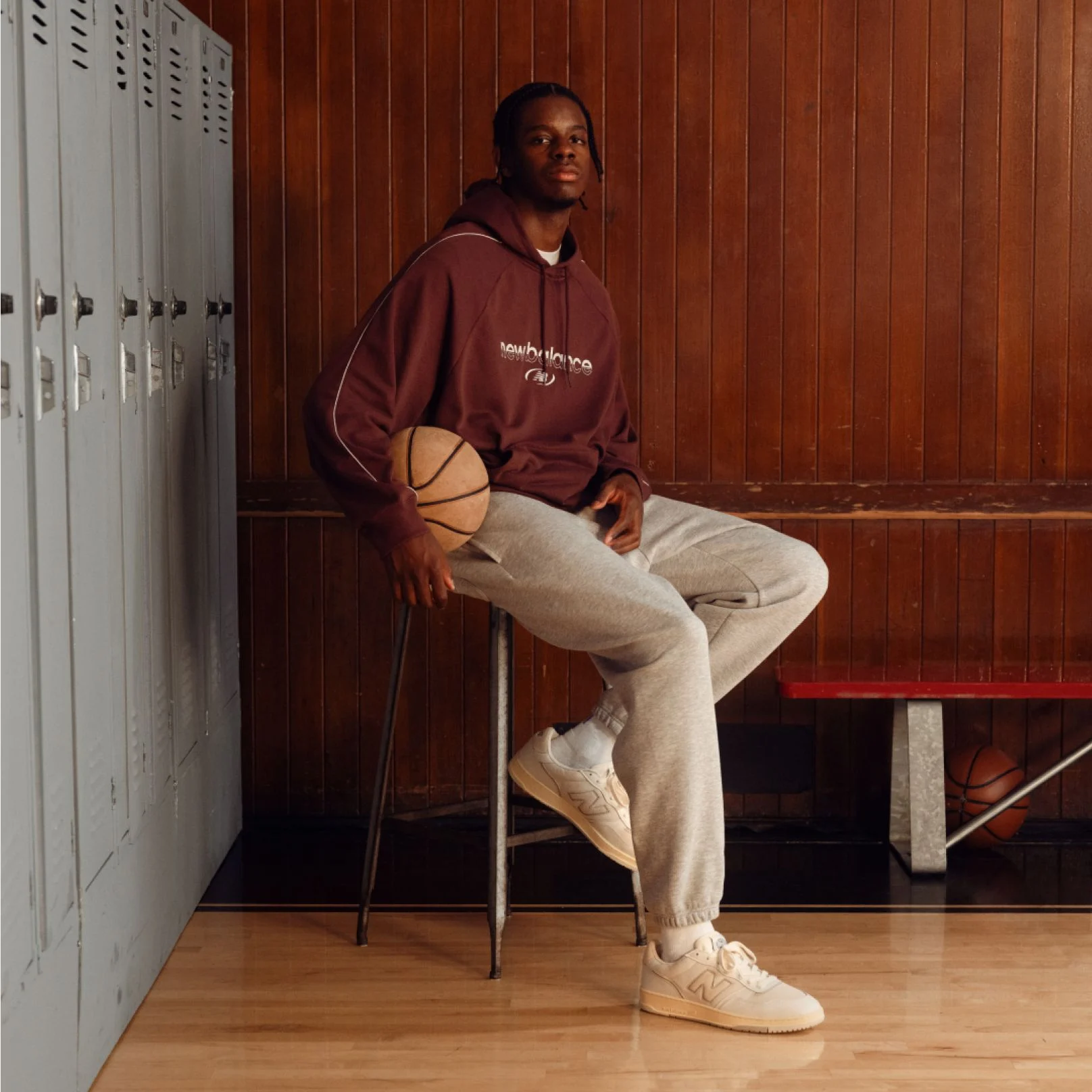 Caleb Wilson sitting on a stool, holding a basketball in a locker room.