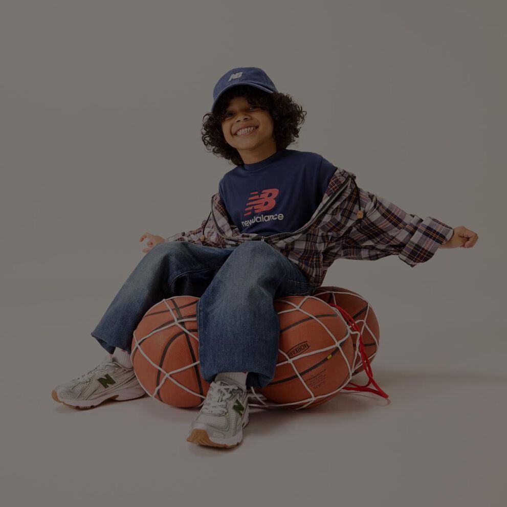 Un niño sentado en una red de pelotas de baloncesto.