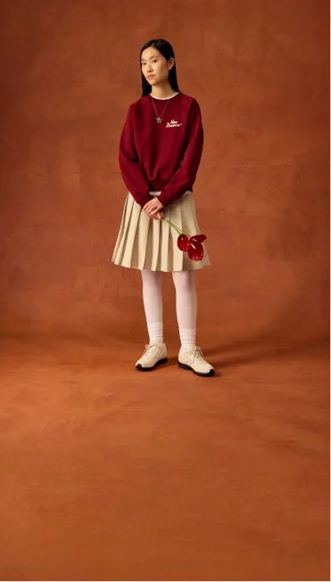 Woman standing with a beige skirt holding flowers.