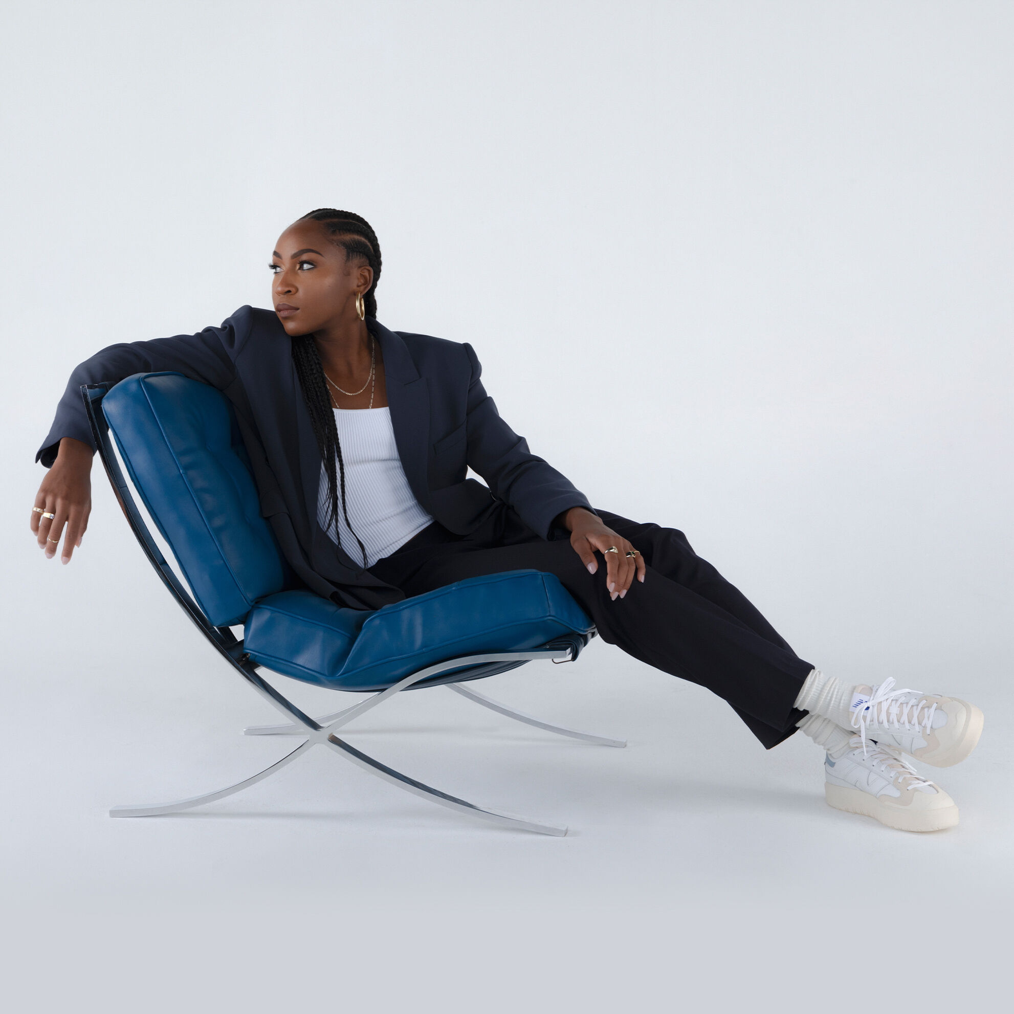 Tennis star, Coco Gauff, sitting on a blue chair wearing a pair of CT302 shoes