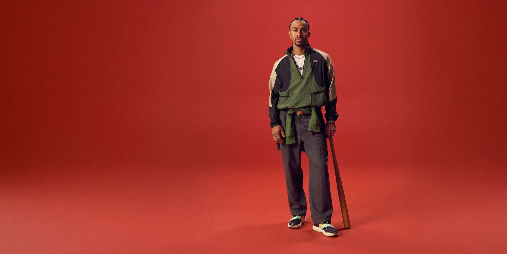 Baseball athlete holding a bat on a red background.