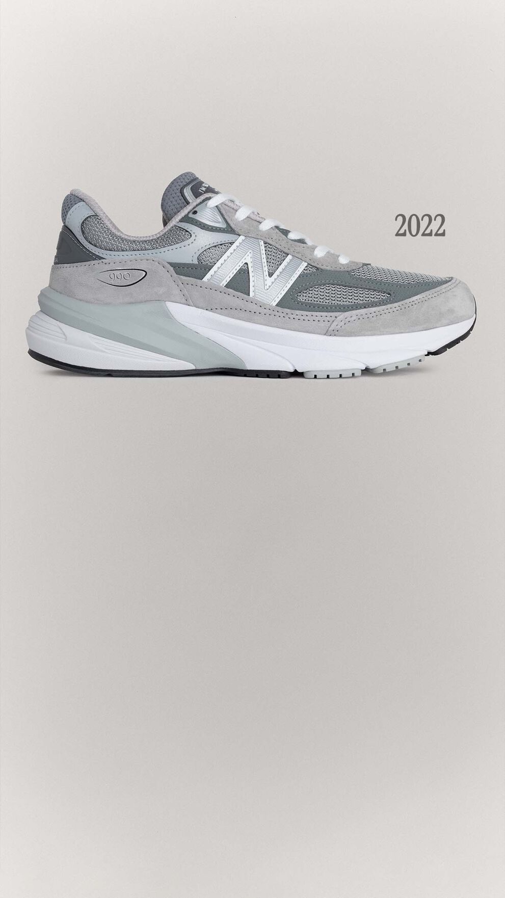 A grey 990v6 sneaker sitting on a grey background.
