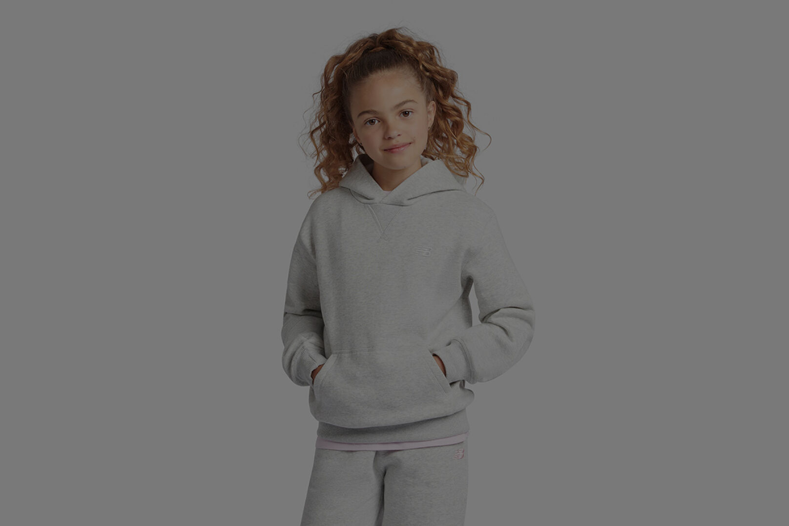 Girl in grey New Balance hoodie and matching sweatpants. 