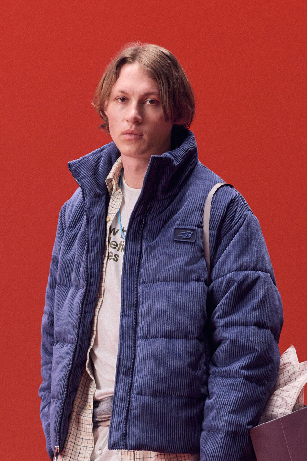 Young man in a blue jacket carrying a bag of gifts on a red background.