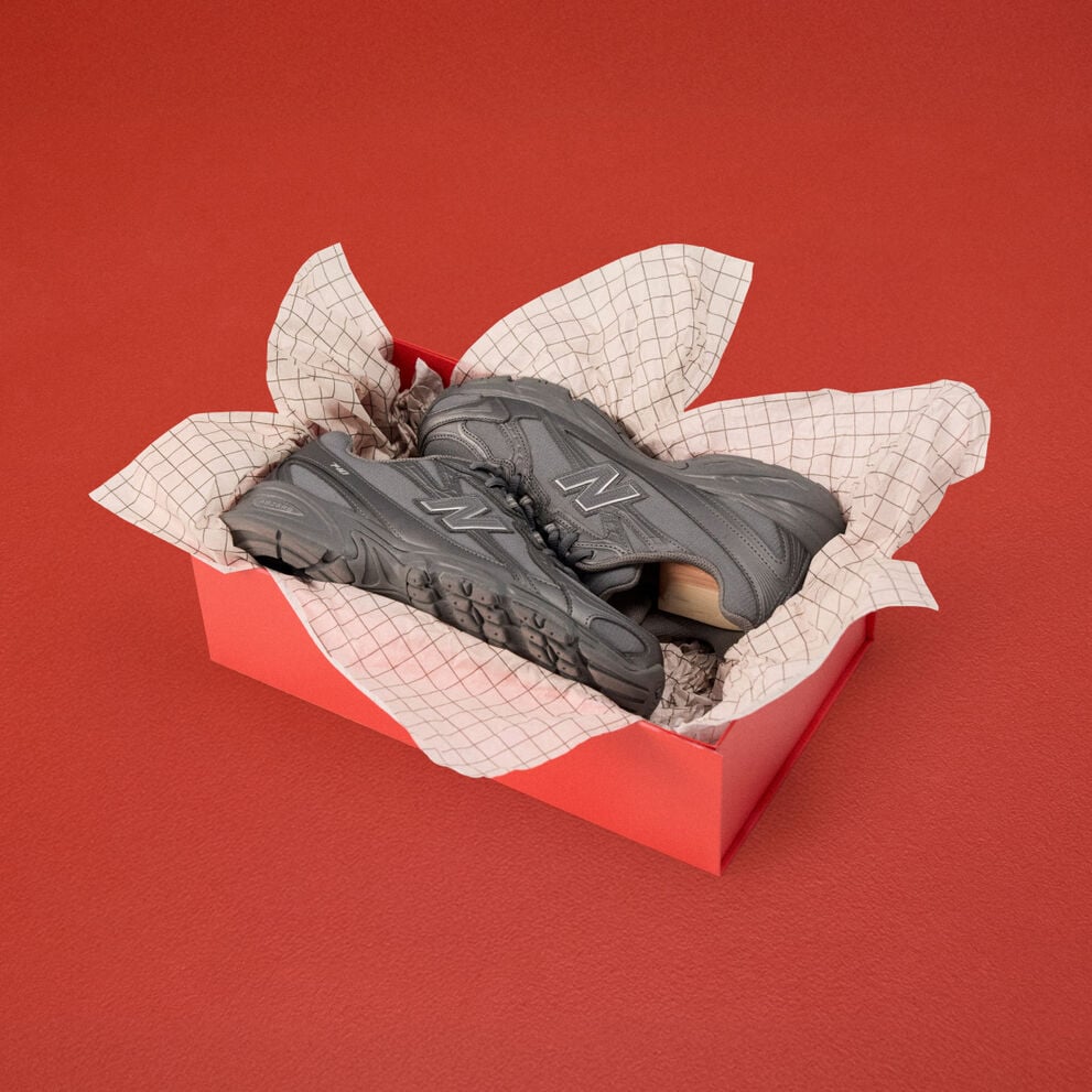 Pair of grey shoes in a box with wrapping paper.