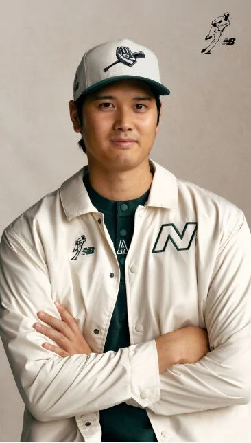 Ohtani wearing a white hat and jacket with his arms folded and smiling.