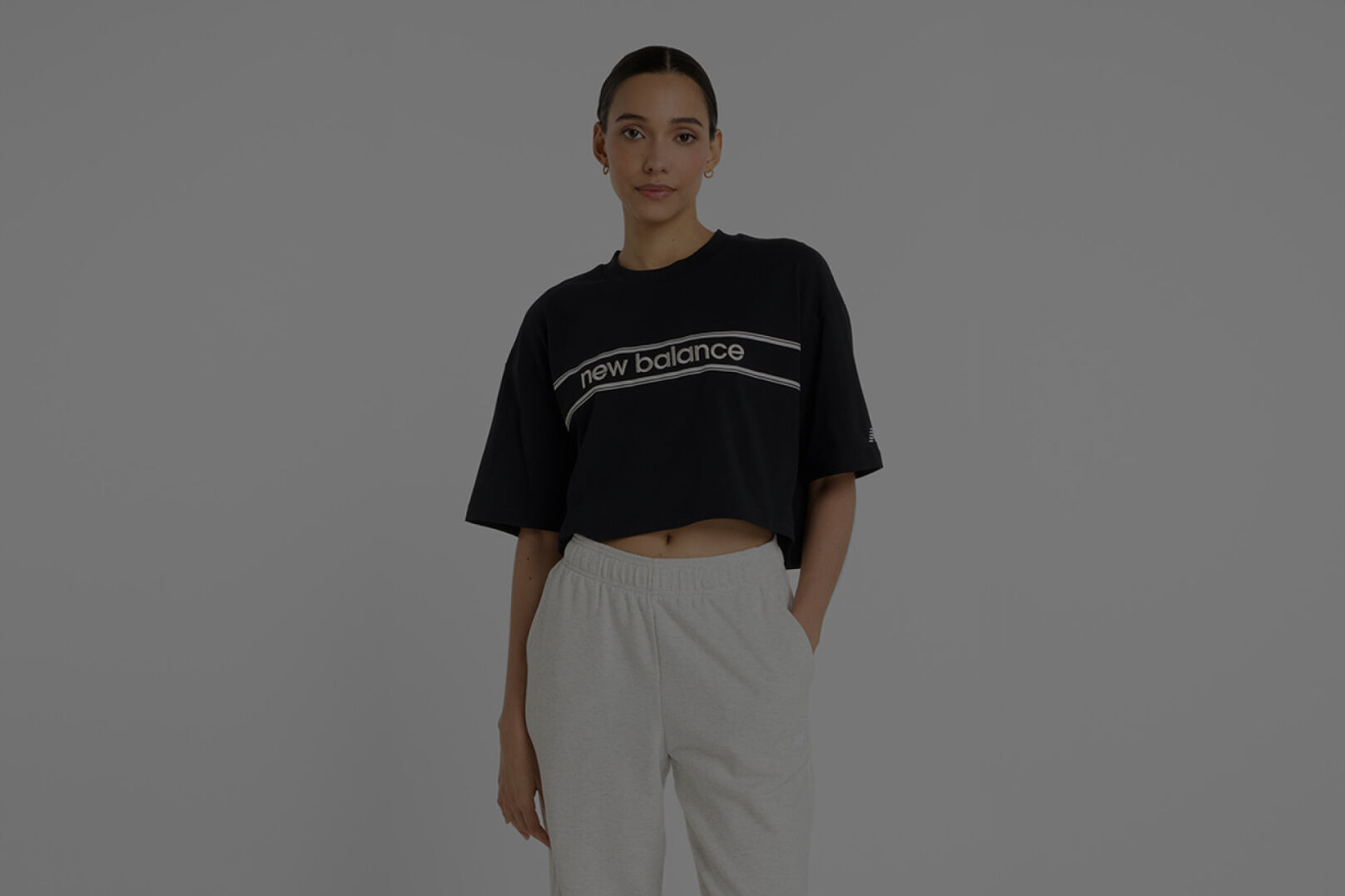 Woman wearing black New Balance shirt and grey New Balance joggers.