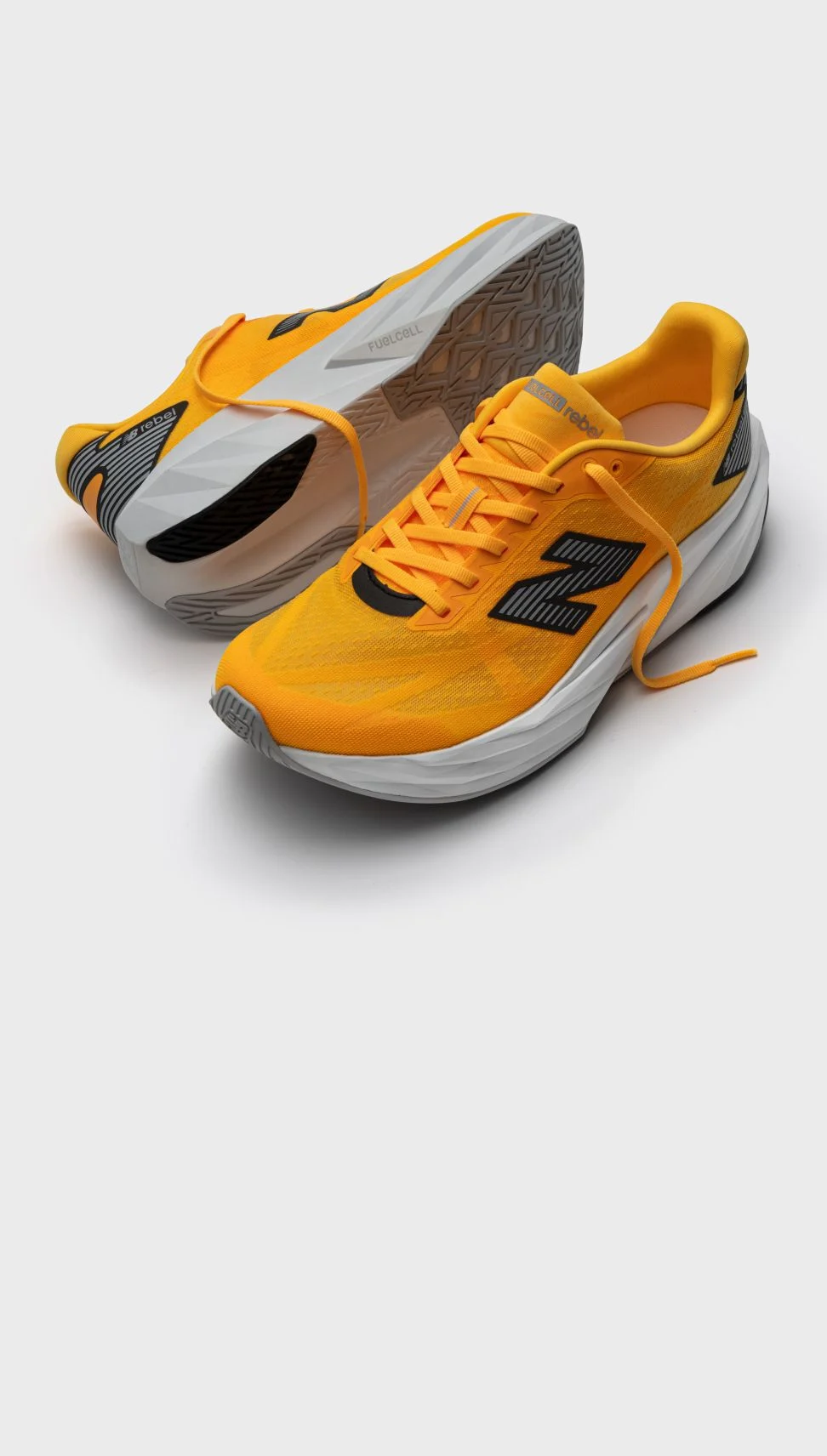 A pair of orange FuelCell Rebel shoes on a grey background.&nbsp;