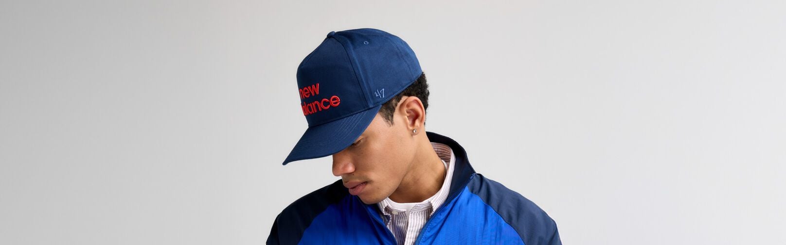 A close-up shot of a male looking to the side while wearing a navy &lsquo;47 hat. 