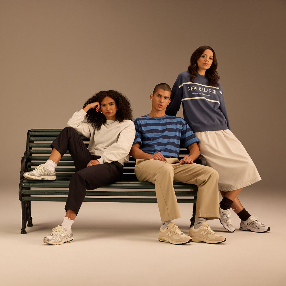 Group of men and women wearing New Balance running clothing and shoes posed against beige background in studio environment