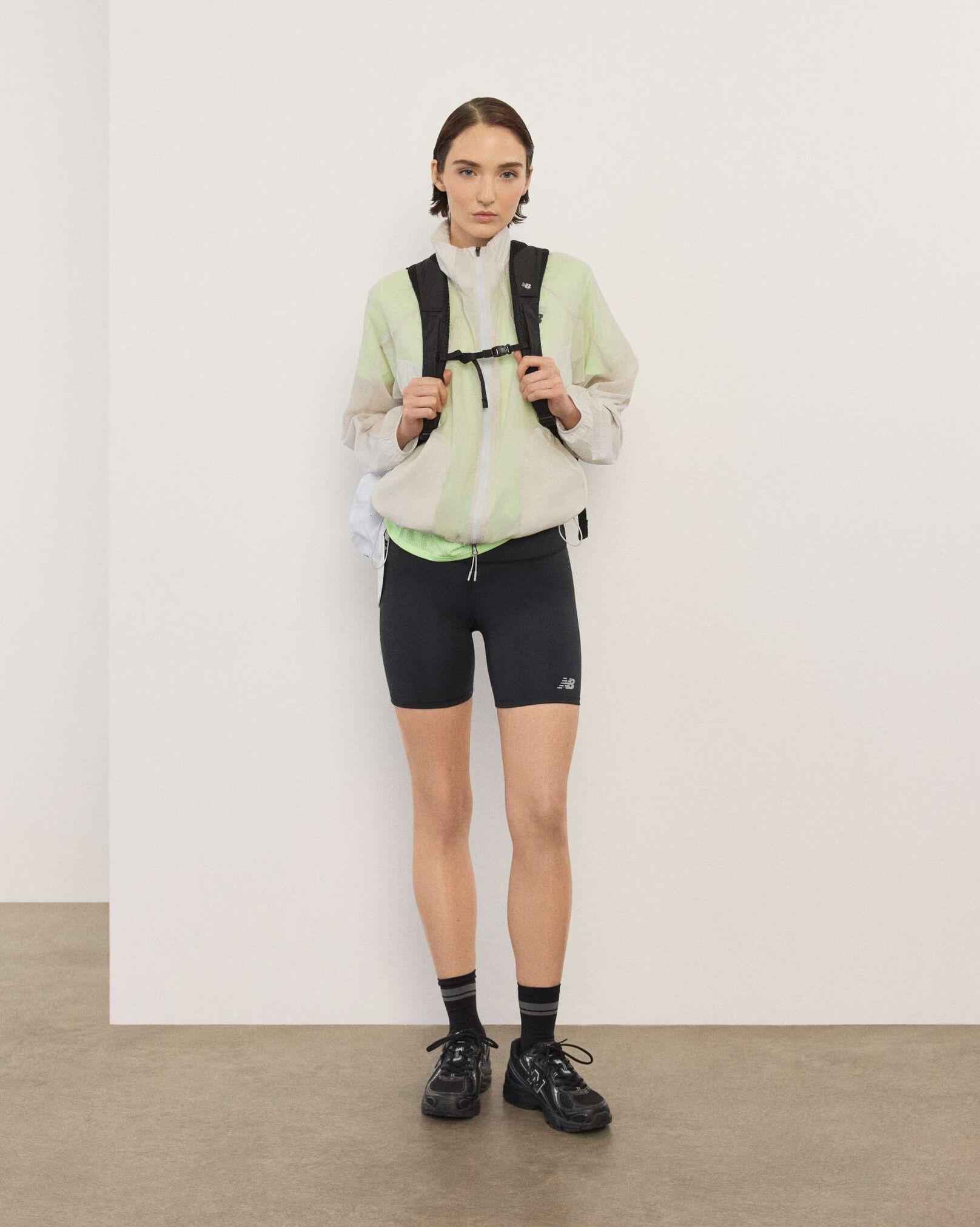 A woman standing in front a white wall.