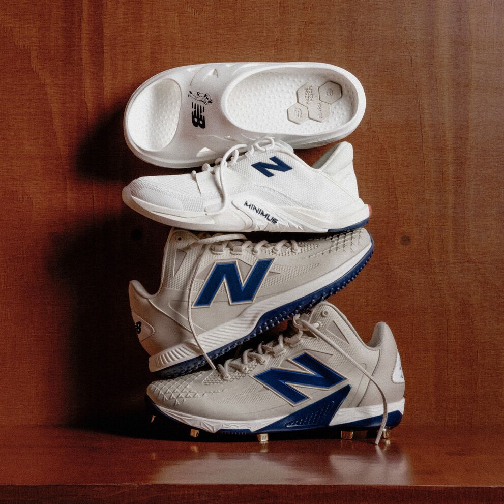 Four different shoes and cleats sitting on top of each other on a wooden bench. 