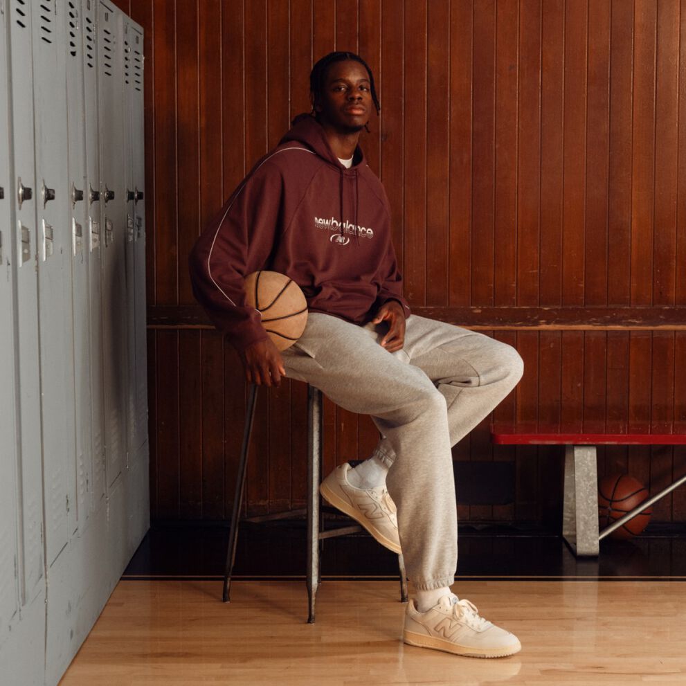Caleb Wilson sitting on a stool, holding a basketball in a locker room.