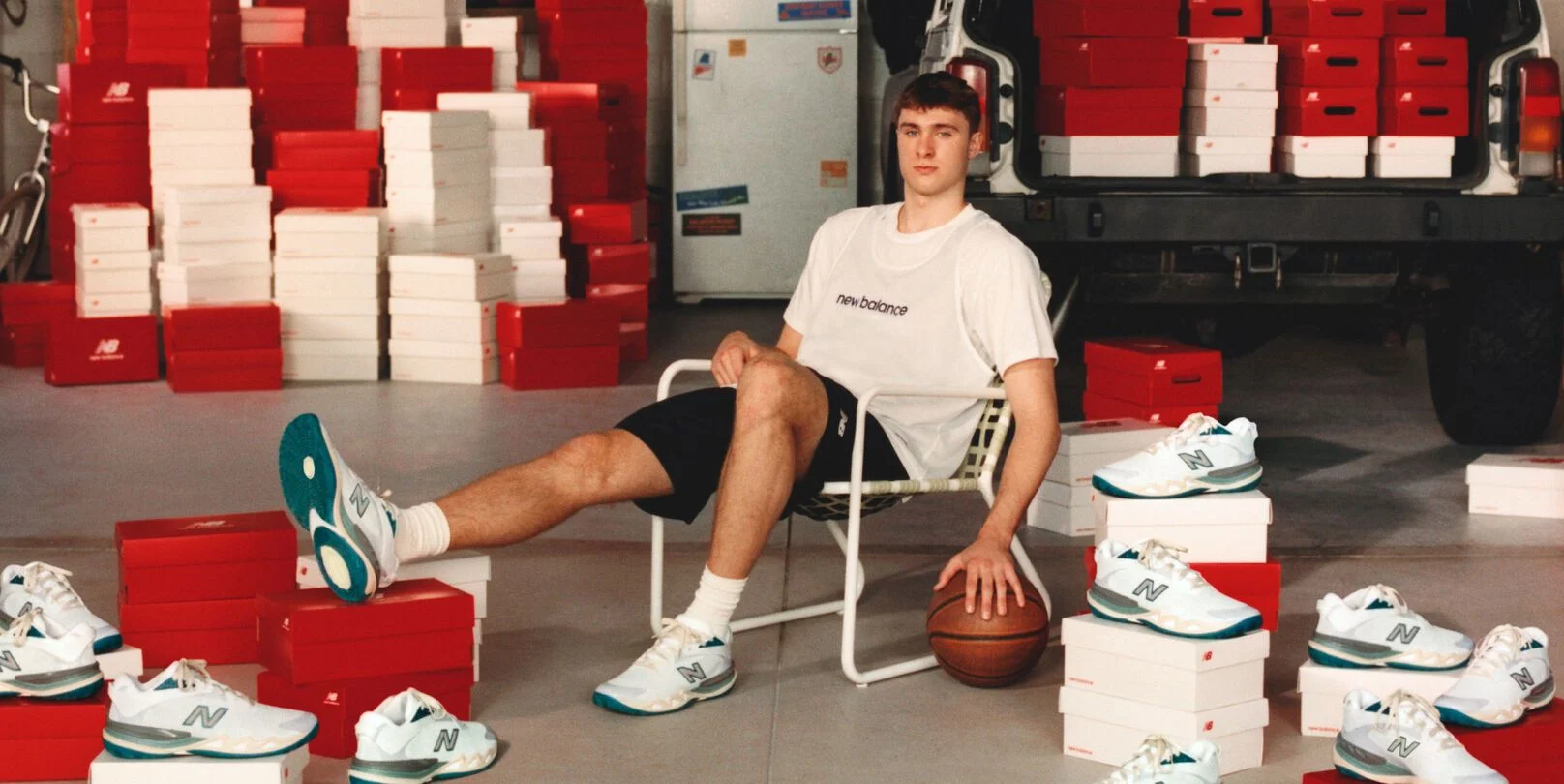 Young athlete sitting in a chair by his garage with shoes all around him.