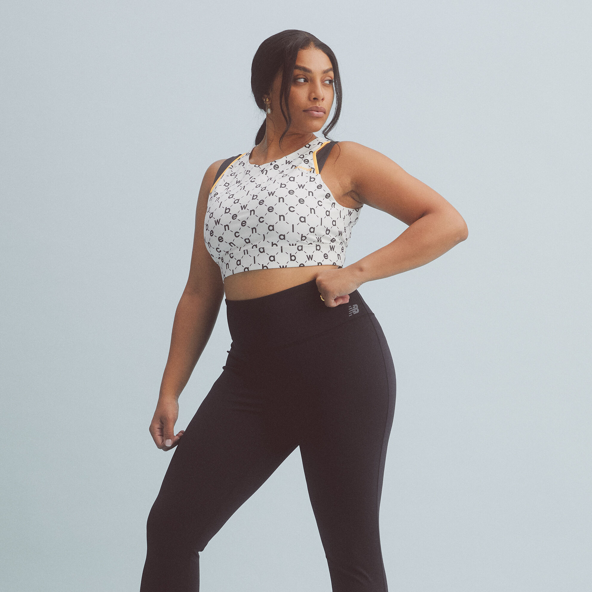 Young lady wearing a crop top and black tights looking to her left.