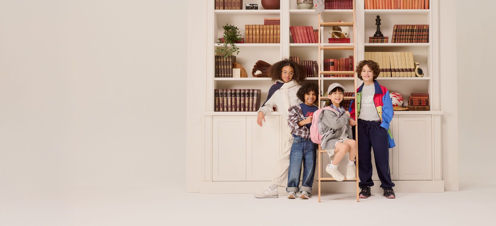 Group of young kids standing in front of a bookshelf. 