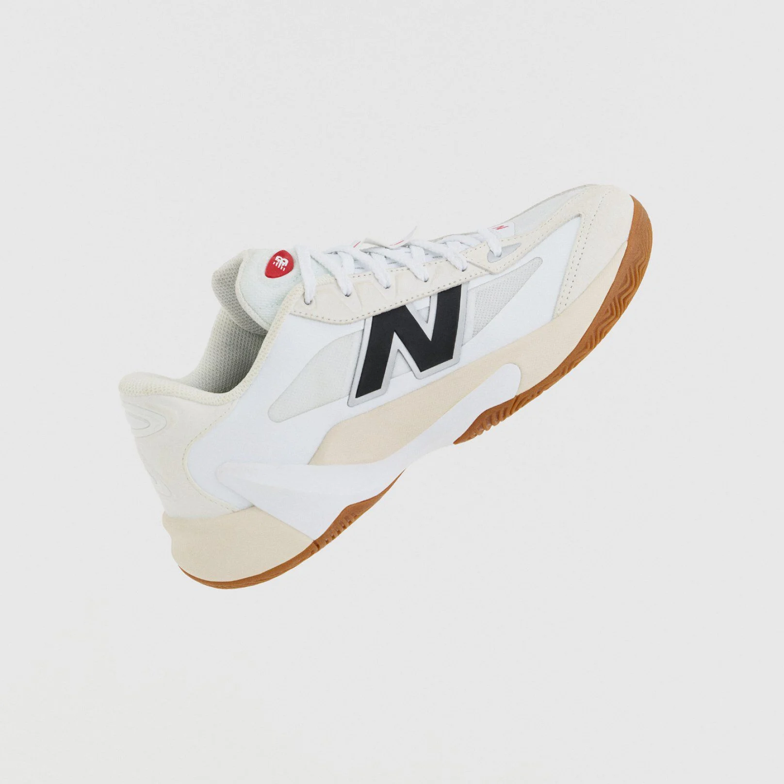 A white athletic shoe with beige accents, a gum outsole, and a large black &ldquo;N&rdquo; logo is shown against a plain white background.