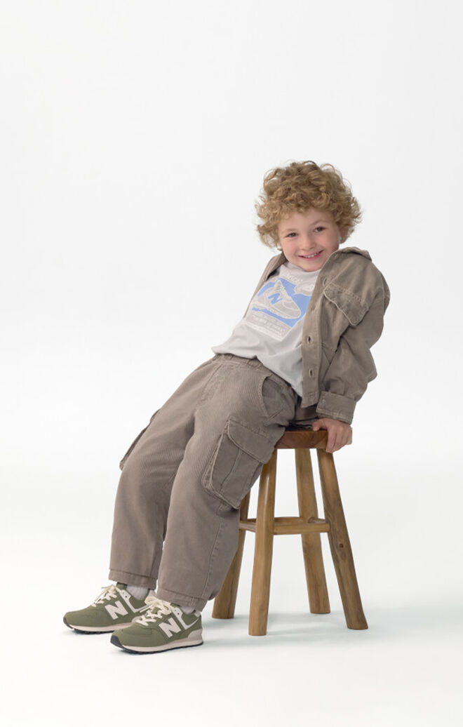 Niño apoyado en una silla de madera