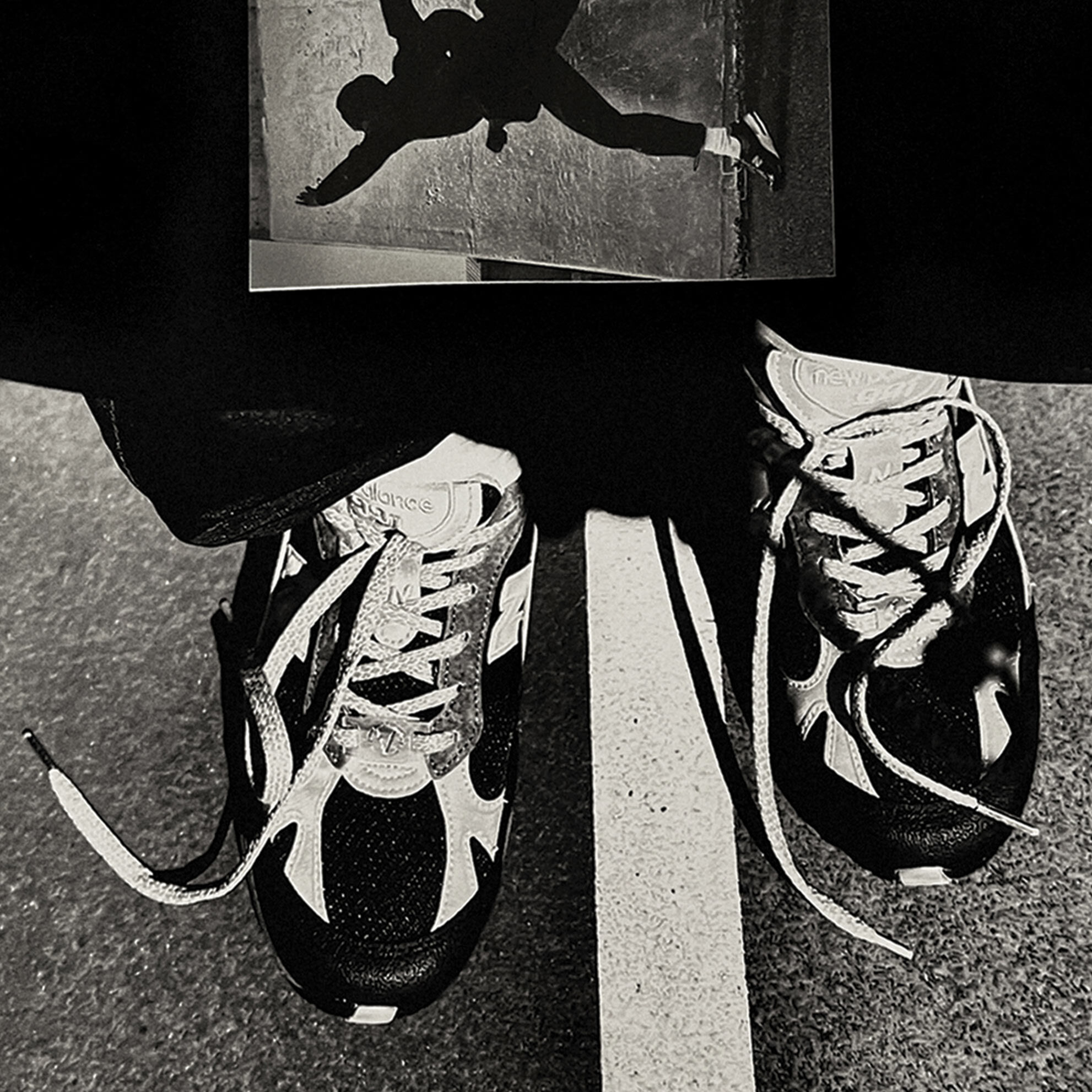 Top-down crop of a pair of NB Made in UK 991 sneakers standing on an outdoor basketball court