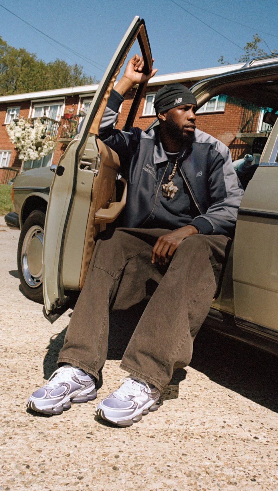 Man sitting in a car with the door open wearing purple New Balance sneakers.