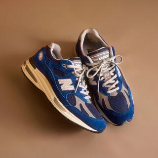 Un par de zapatillas New Balance Made in UK en un estudio de color beige.