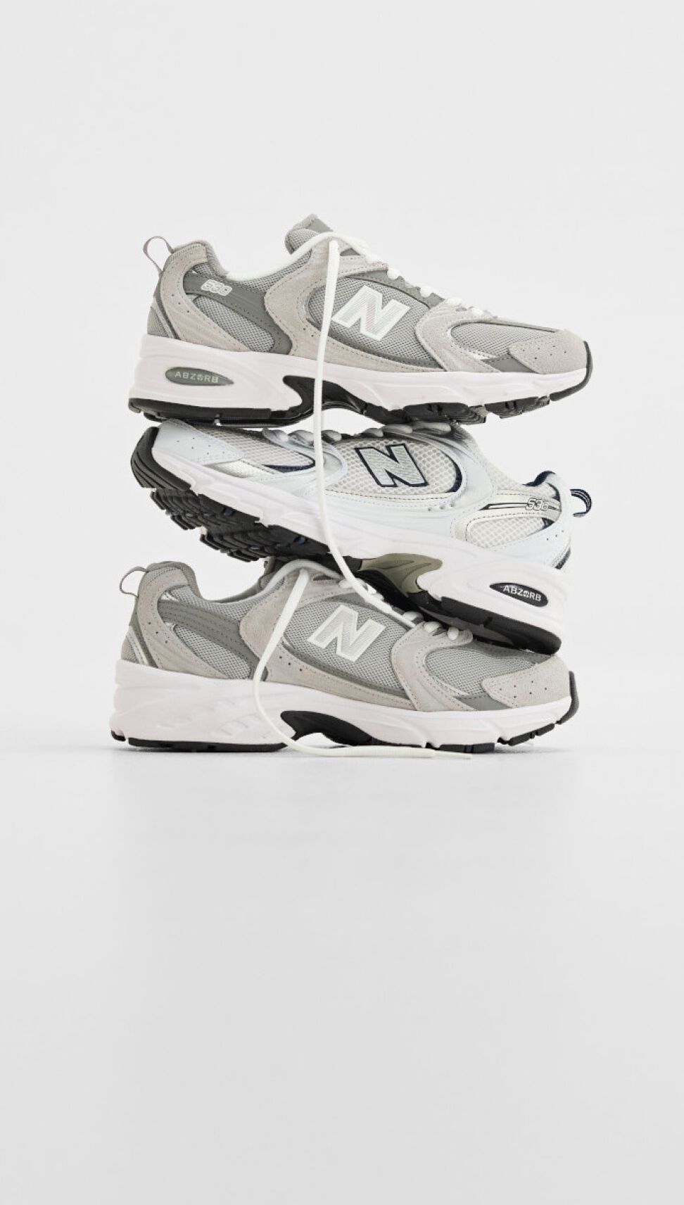 Stack of three New Balance sneakers on white background.